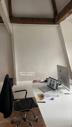 an office desk with a laptop computer on top of it next to a black chair