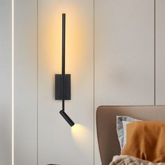 a black wall light mounted on the side of a white wall next to a bed