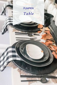 the table is set with black and white plates, napkins, and silverware