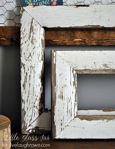 an old white frame is sitting on a table next to a chicken wire wallpaper