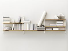 a book shelf filled with books on top of each other next to a white wall