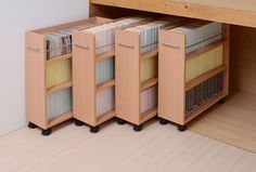 an open cabinet with many files and folders on wheels in front of a wooden desk