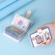 a hand holding a small wallet next to a stack of cards