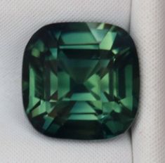 an emerald colored stone sitting on top of a white cloth