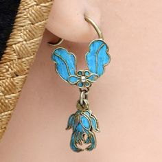 These dangle earrings are antiques that originate from the Qing Dynasty, where a noble woman would have worn an intricate design such as this for a special occasion.Antique stock, made by hand in the late 19th or early 20th century. Gilded silver with kingfisher feather (tian-tsui) finish depicts an arrangement of flowers and leaves. 1 1/4 inches tall with french hook ear wires. Vintage Ceremonial Drop Earrings, Vintage Drop Earrings For Ceremonial Occasion, Antique Ceremonial Earrings, Vintage Ceremonial Earrings With Intricate Design, Ceremonial Vintage Earrings With Intricate Design, Ornate Bronze Earrings, Vintage Brass Earrings For Ceremonial Occasions, Ornate Antique Finish Earrings As Gift, Ornate Antique Finish Earrings For Gifts