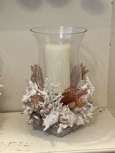 a candle is sitting on a shelf next to some seashells and other items