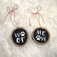 two wood slices with the words woof and meow painted on them hanging from red twine