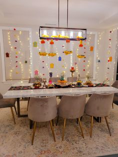 a dining room table set for four with lights on the wall behind it and decorations hanging from the ceiling