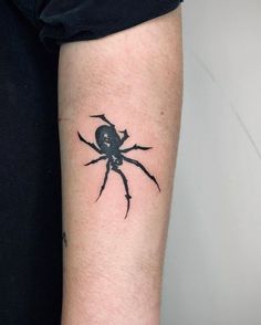 a black spider tattoo on the arm