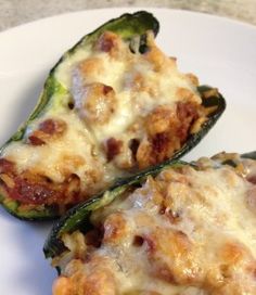 two stuffed green peppers on a white plate