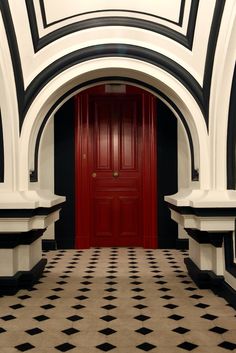 a red door is in the middle of a black and white checkerboard floor