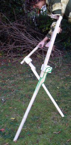 a man is bending over to pick up something out of the ground with a pair of scissors