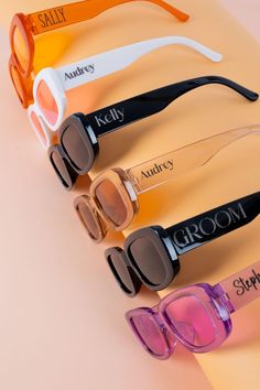 four pairs of sunglasses with different colors and shapes on top of each other, sitting on a table