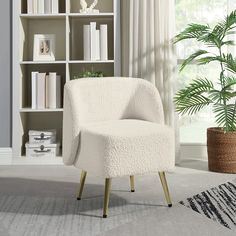 a white chair sitting in front of a book shelf next to a potted plant