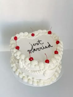 a heart shaped cake with cherries on top and the words just married written on it