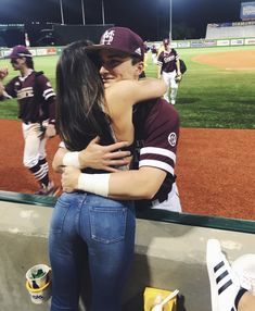 two people embracing each other at a baseball game