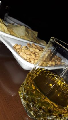 a glass filled with liquid sitting on top of a table next to a plate of food