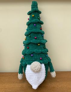 a crocheted christmas tree sitting on top of a wooden table next to a wall