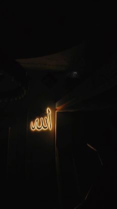 a neon sign that is on the side of a building in the dark with light coming from it