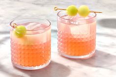 two glasses filled with drinks sitting on top of a marble counter next to each other