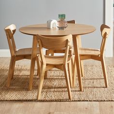 a wooden table with four chairs and a vase on top of it in a room