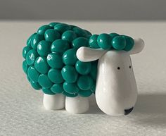 a green and white sheep figurine sitting on top of a table next to a wall