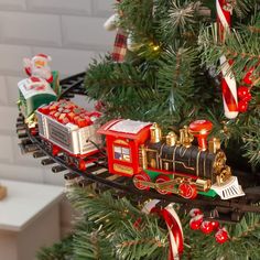 a christmas tree with a train ornament hanging from it's side and decorations on top