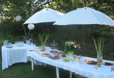 an outdoor table set up with food and umbrellas