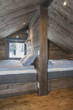 there are two beds in the attic with wooden walls and flooring on each side