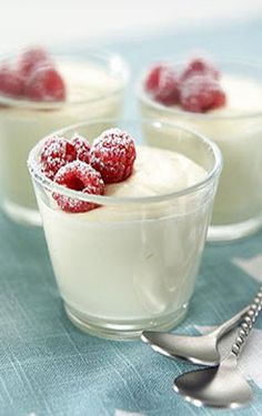 three small desserts with raspberries in them on a blue and white table cloth