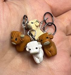 a hand holding several cow key chains in it's palm