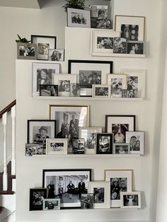 a bunch of pictures are hanging on the wall next to some stairs and railings