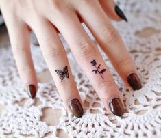 a woman's hand with a butterfly tattoo on her left thumb and the other finger