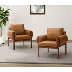 two brown leather chairs sitting on top of a rug next to a potted plant