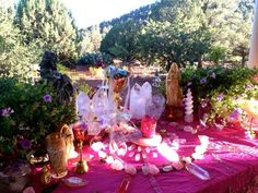 a table covered with candles and vases on top of a purple clothed tablecloth