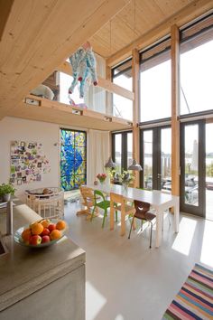 a dining room table with fruit on it in front of large windows and wooden beams