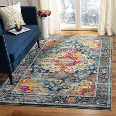 a living room area with a blue couch and colorful rugs on the hardwood floor