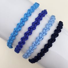 four crocheted bracelets on top of a white wristband, one blue and one black