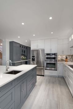 a large kitchen with stainless steel appliances and white counter tops