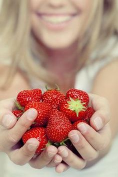 a woman is holding some strawberries in her hands