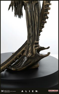 an alien statue is shown on a black base with the legs and feet extended up