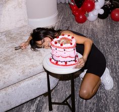 a woman leaning over a table with a cake in front of her on the floor