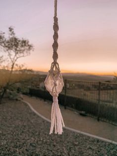 a wind chime hanging from the side of a road at sunset or dawn with mountains in the background