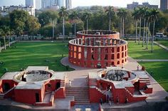 an aerial view of a circular building in the middle of a park with stairs leading up to it