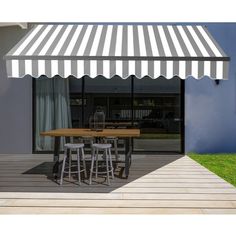 an awning on the outside of a building with four stools and a table