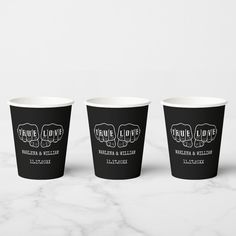 three black paper cups with white lettering on them