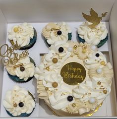 cupcakes with white frosting and gold decorations in a box