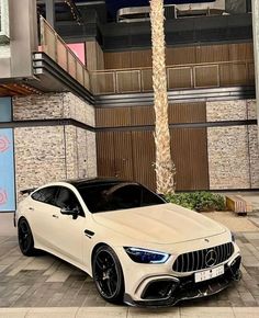 a white mercedes cla parked in front of a tall building with palm trees on the sidewalk