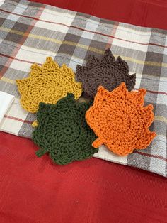 four crocheted flowers sitting on top of a plaid tablecloth covered in fabric