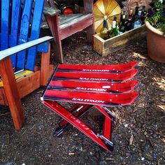 three red skis sitting on top of a wooden bench next to a blue chair